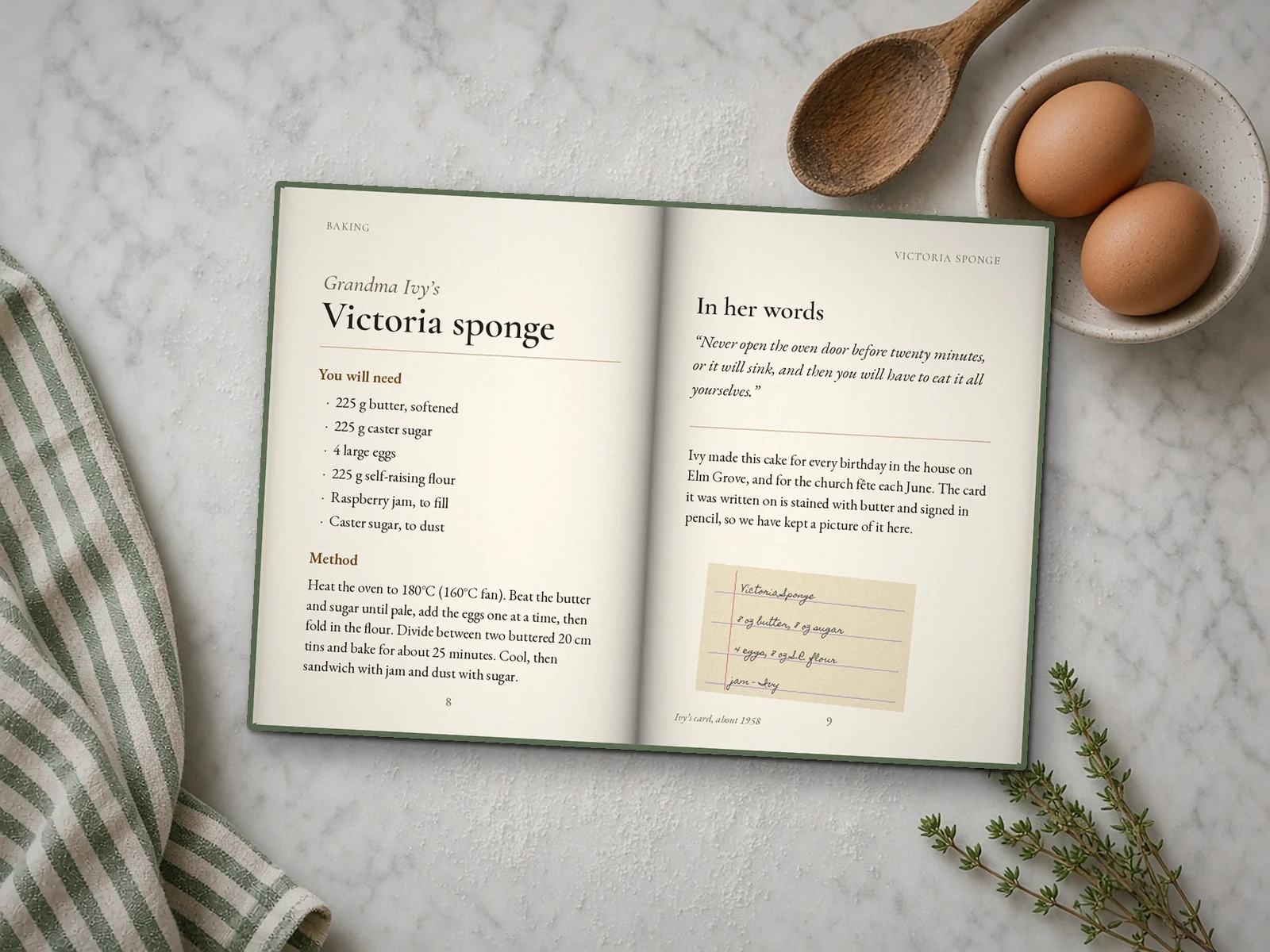 Illustration of a Family Recipe Keepsake open at Grandma Ivy's Victoria sponge (a sample name), with a picture of her handwritten card, on a marble worktop